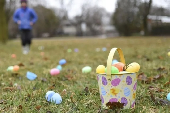 Bucket of colorful eggs on grass, person running in background.