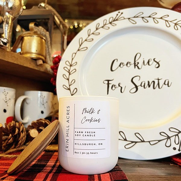 Soy candle and Santa plate on a plaid cloth with holiday decor.