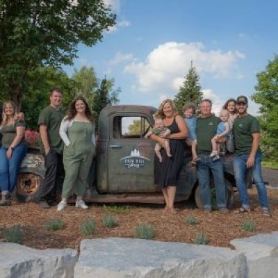 Group of people standing around a vintage truck outdoors on a sunny day.