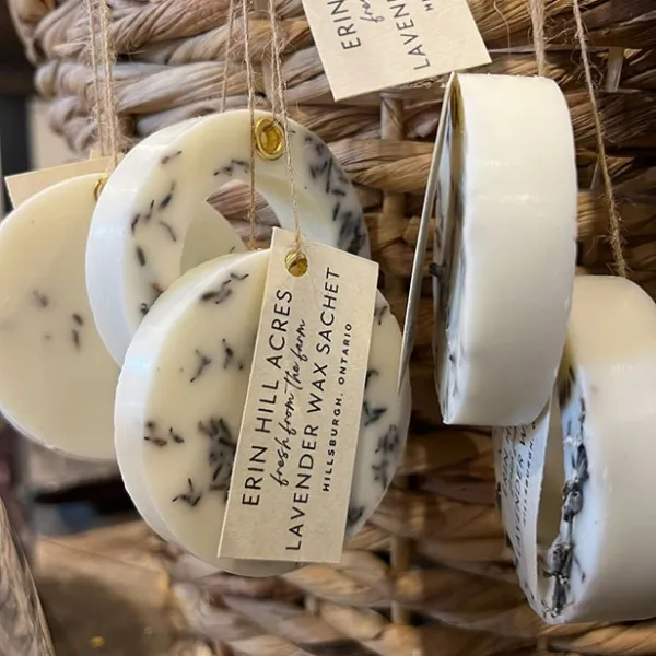 Lavender wax sachets hanging from a basket with tags.
