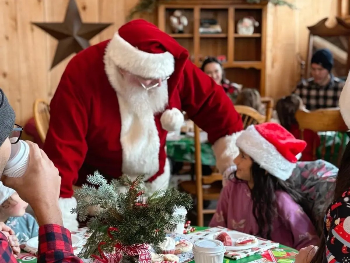 Santa Claus interacting with a child at a festive table, indoors.